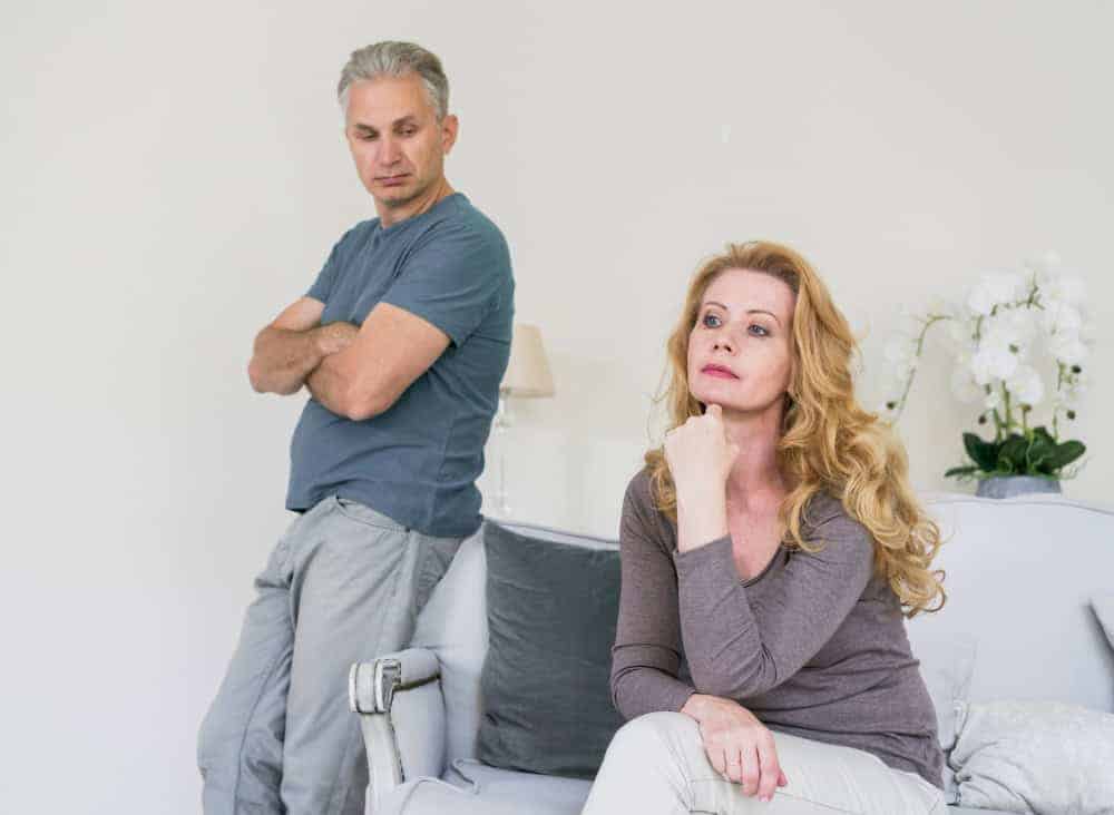 Unhappy couple sitting together at home